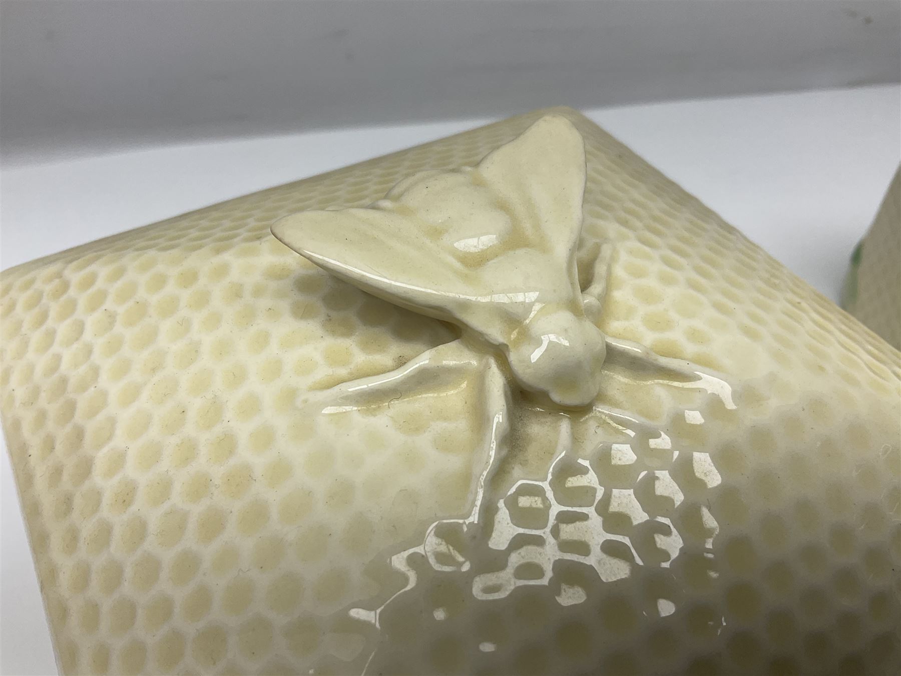 Four square honey boxes with lids,  each decorated with honeycomb pattern and finished with a bee finial