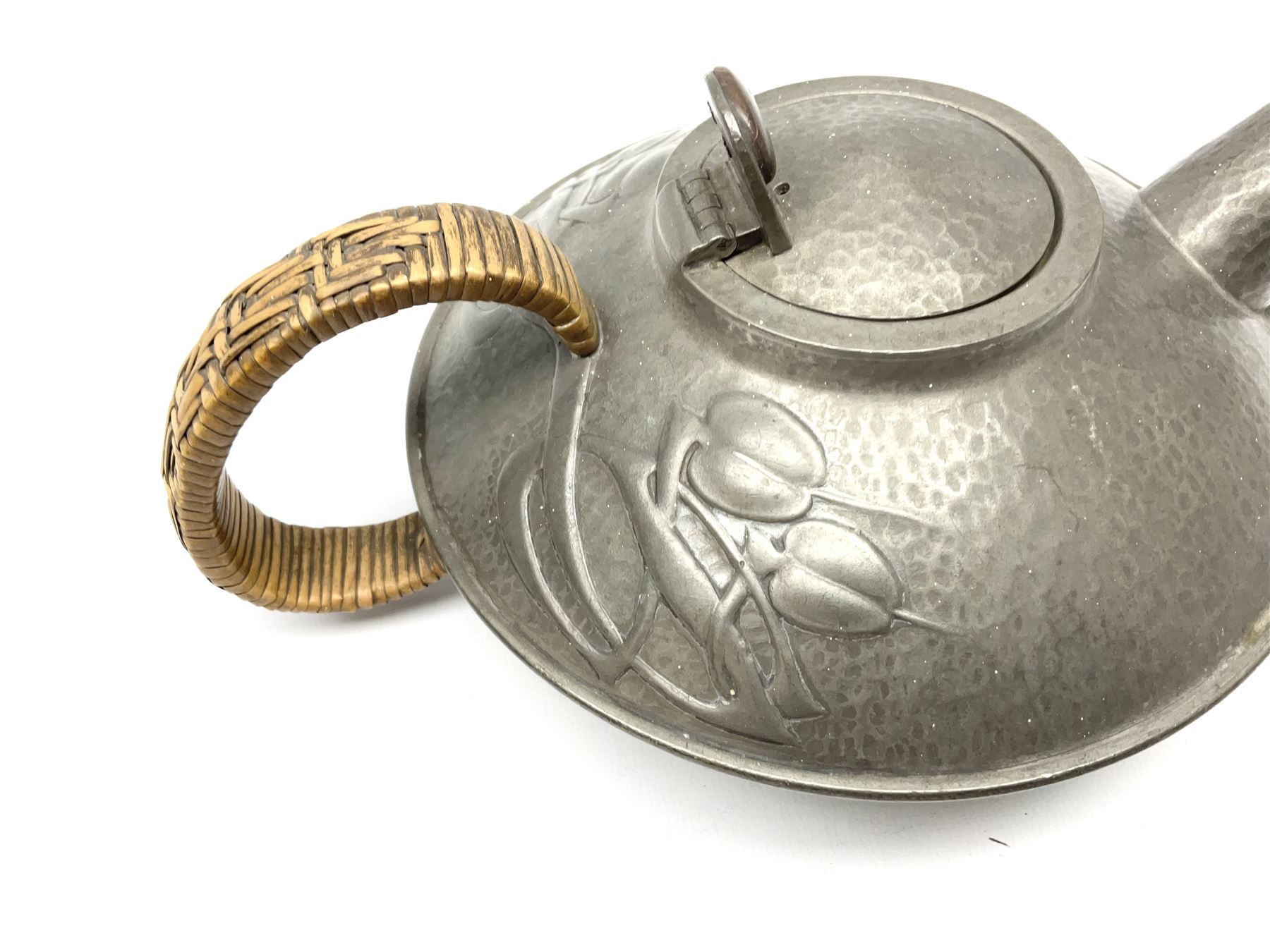 Archibald Knox for Liberty & Co Tudric pewter three piece tea service, comprising teapot with woven reed handle, single handled open sucrier, and milk jug, each with planished finish and detailed with honesty flowers, each impressed beneath Made in England Tudri Pewter 0231 