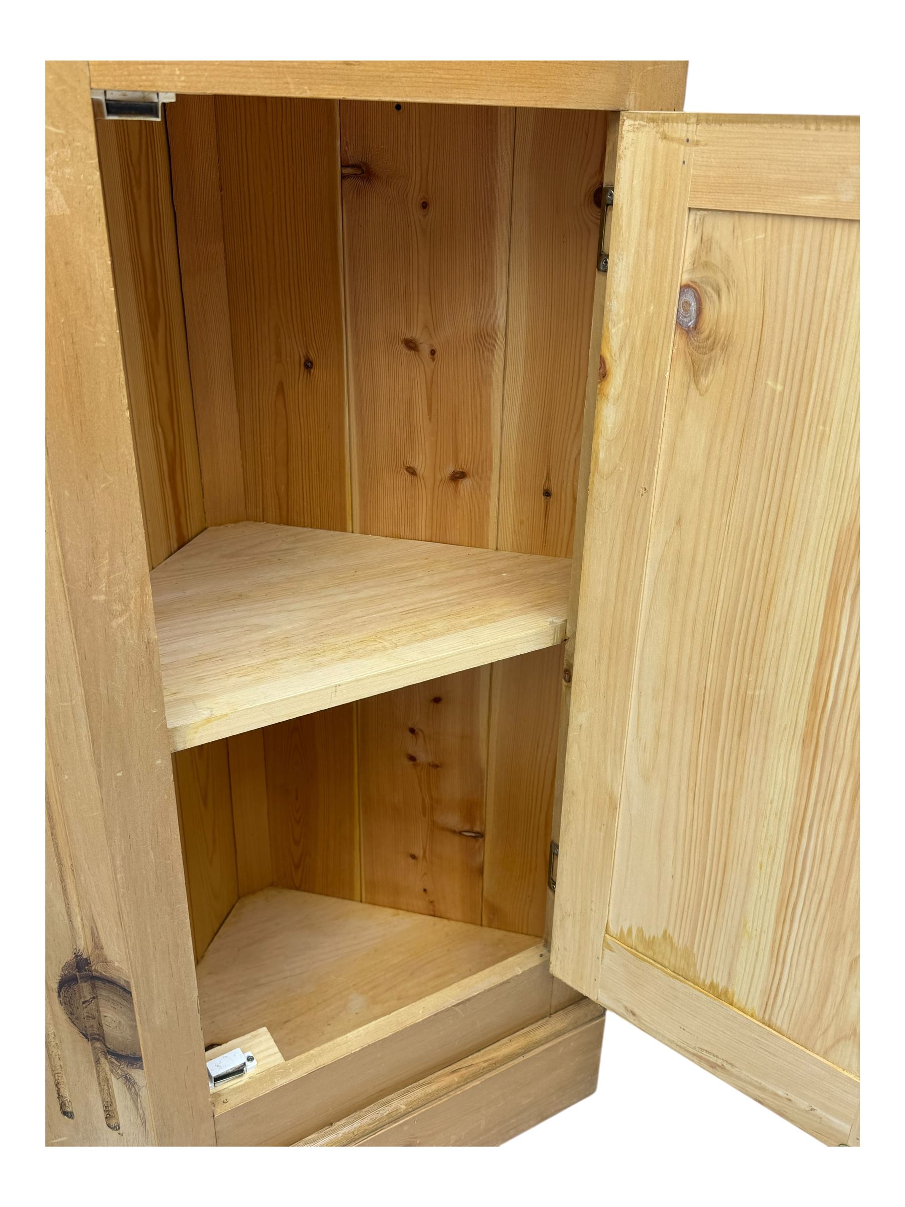 Early 20th century pine corner cabinet, projecting cornice over three shaped shelves, base fitted with single door enclosing storage space with a recessed panel, fluted sides, on plinth base