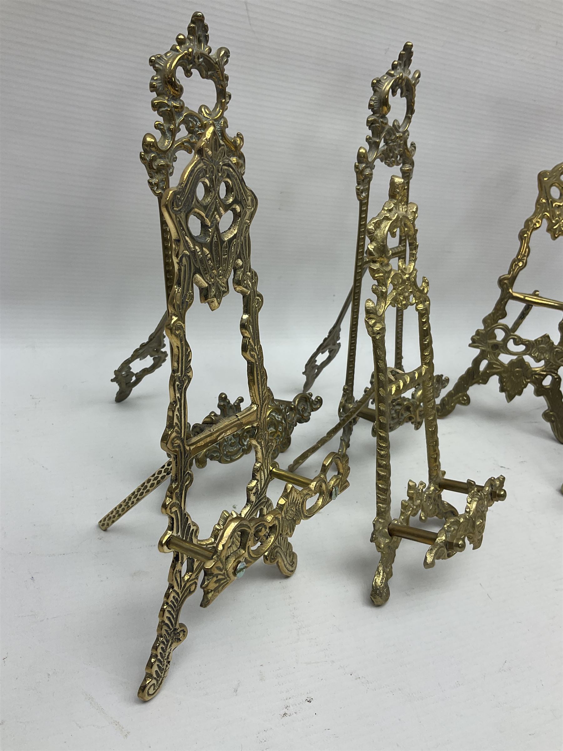 Nine ornate cast brass easel stands of various sizes, H24cm