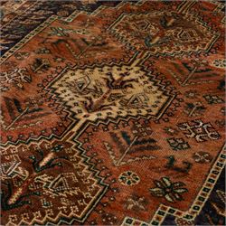 South West Persian Qashqai hand-knotted rug, salmon pink field with central stepped geometric medallion with issuing stylized tree and floral motifs, surrounded by angular devices, with indigo spandrels and multiple geometric borders, fringe ends 