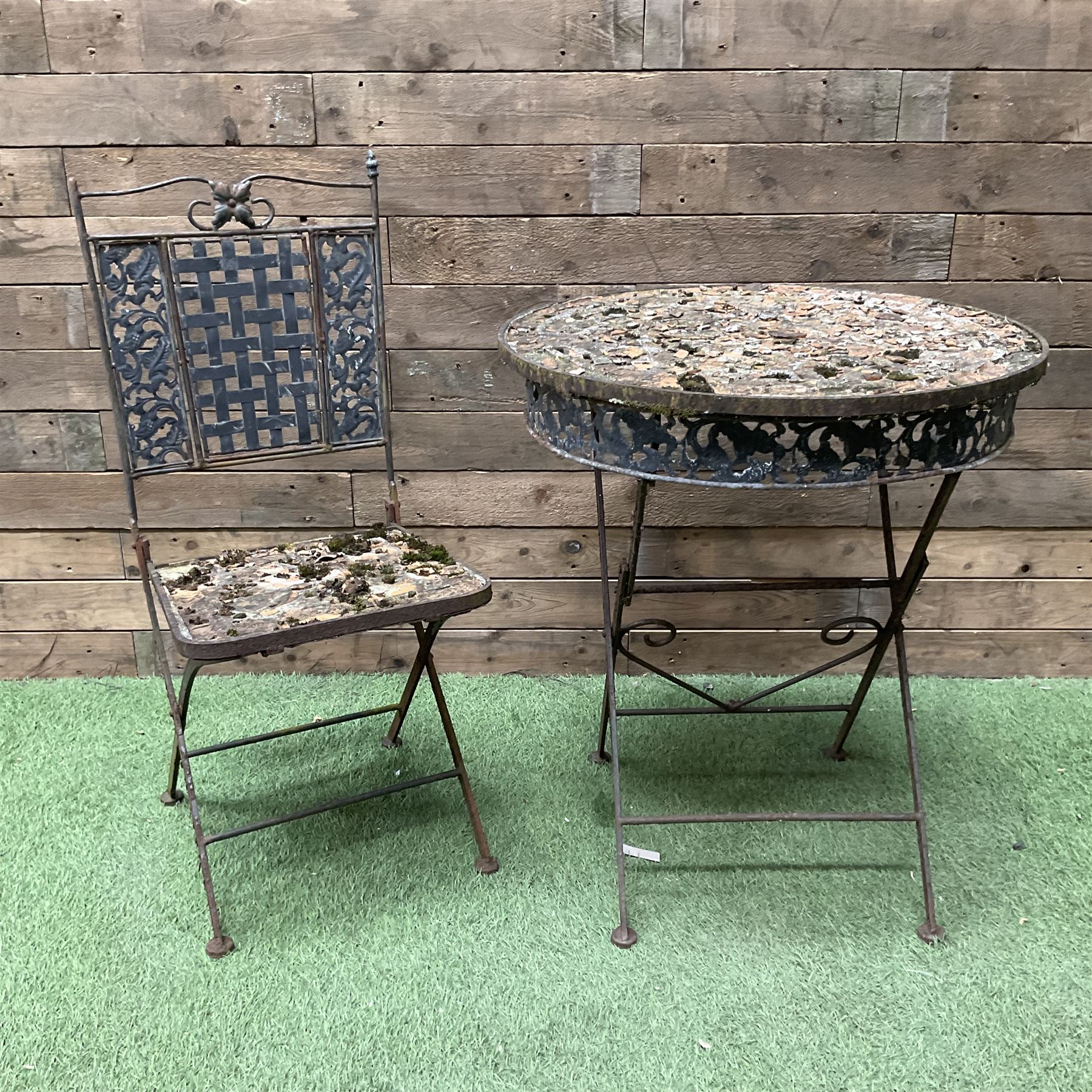 Circular metal garden table with tile top and matching chair, weathered