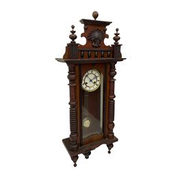 A  German spring driven wall clock c1900 within a glazed case with side panels and a full-length arched door and ornately carved pediment, turned finials and original pendant finials, with a 5' two-piece white enamel dial with roman numerals, minute markers and pierced steel gothic hands, with a visible gridiron pendulum with an R/A inscribed pressed brass bob, eight-day movement striking the hours and half hours on a coiled gong.  



