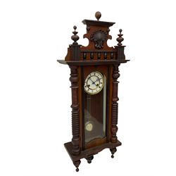A  German spring driven wall clock c1900 within a glazed case with side panels and a full-length arched door and ornately carved pediment, turned finials and original pendant finials, with a 5' two-piece white enamel dial with roman numerals, minute markers and pierced steel gothic hands, with a visible gridiron pendulum with an R/A inscribed pressed brass bob, eight-day movement striking the hours and half hours on a coiled gong.  



