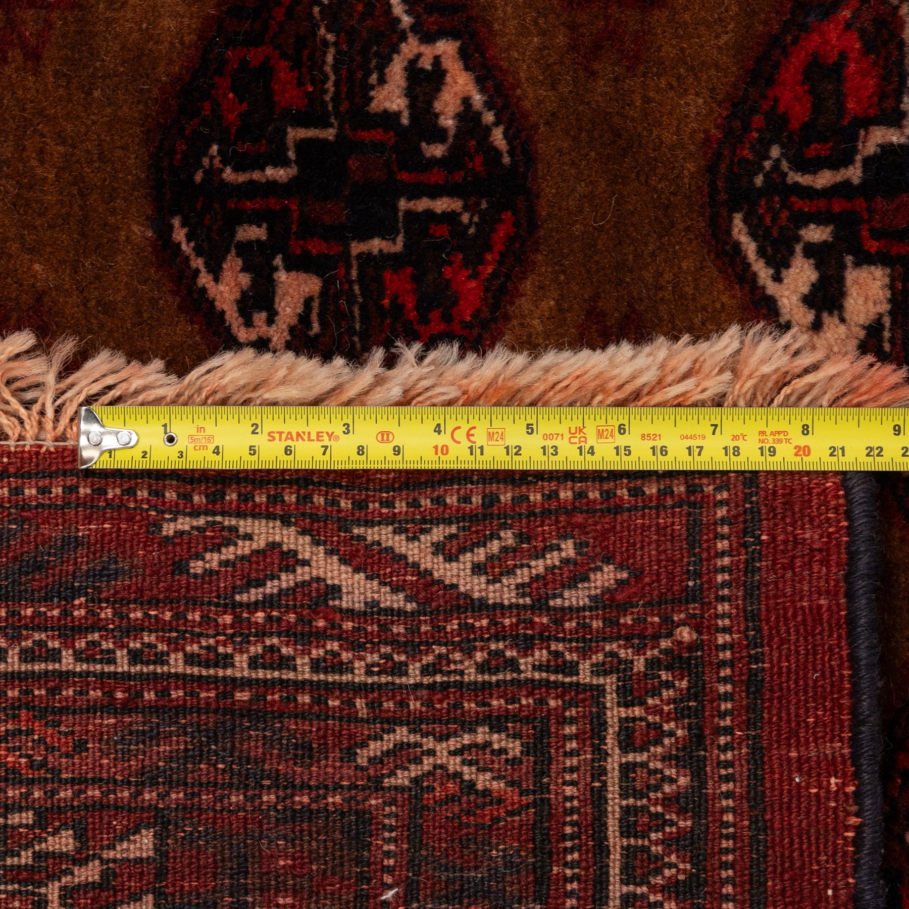 Afghan Bokhara dark amber and terracotta ground rug, decorated with Hac and Gul motifs  within multiple geometric guard bands