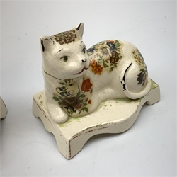 Pair of 19th century Staffordshire cats, modelled in recumbent pose, upon bases with bracket feet, later decorated with transfer printed flowers, H12cm 