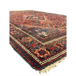 Persian Hamadan red ground rug, the field decorated with floral motifs with central lozenge medallion, guarded border decorated with repeating stylised plant motifs