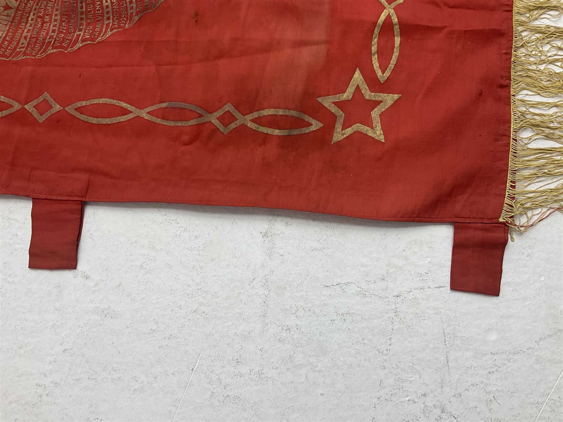 1970s Soviet banner printed in gold on a red ground, roughly translates as 'Transferable Banner - To the winner in the Socialist Competition' and 'Work Study Live by Communism' verso; wreath of wheat ears to either side; tassels on three sides 110 x 155cm