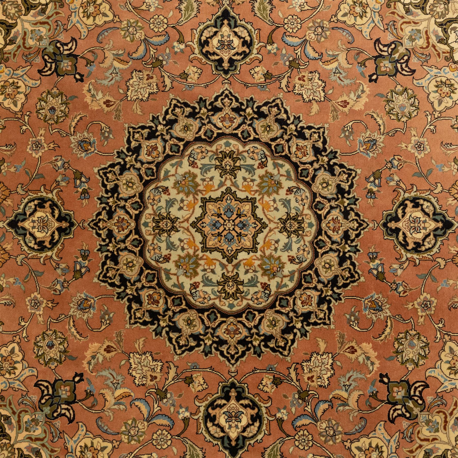 Persian Kashan style rug, salmon pink ground, central conforming lobed medallion in ivory and indigo, with palmette pendants, framed scrolling arabesques of lotus blossoms and palmettes, within navy border of meandering vines and flowerheads between ivory guard stripes 
