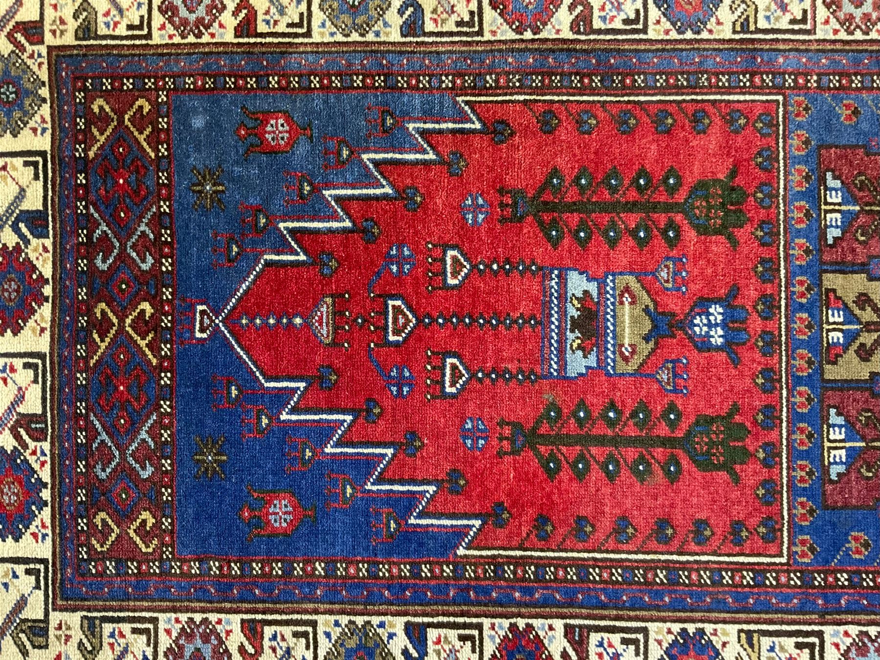 Turkish Yuruk indigo ground rug, the field decorated with geometric architectural designs, the guarded ivory border with repeating stylised plant motifs