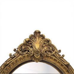 Rococo Revival style gilt composition oval wall mirror, moulded oval frame with fluted and beaded bands enclosing a bevelled mirror plate, the outer frame with acanthus leaf and scroll carved cresting to each side