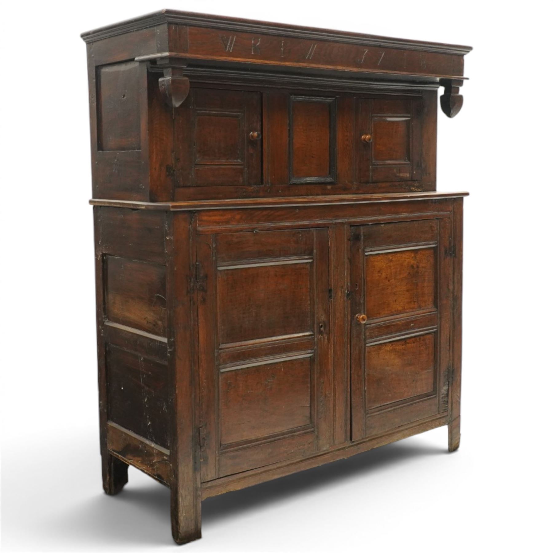 Early 18th century oak court cupboard, the projecting cornice carved with initials 'WKIW' and dated 1718 with turned terminals, fitted with two recessed panelled cupboard doors, large cupboard to base, raised on stile supports