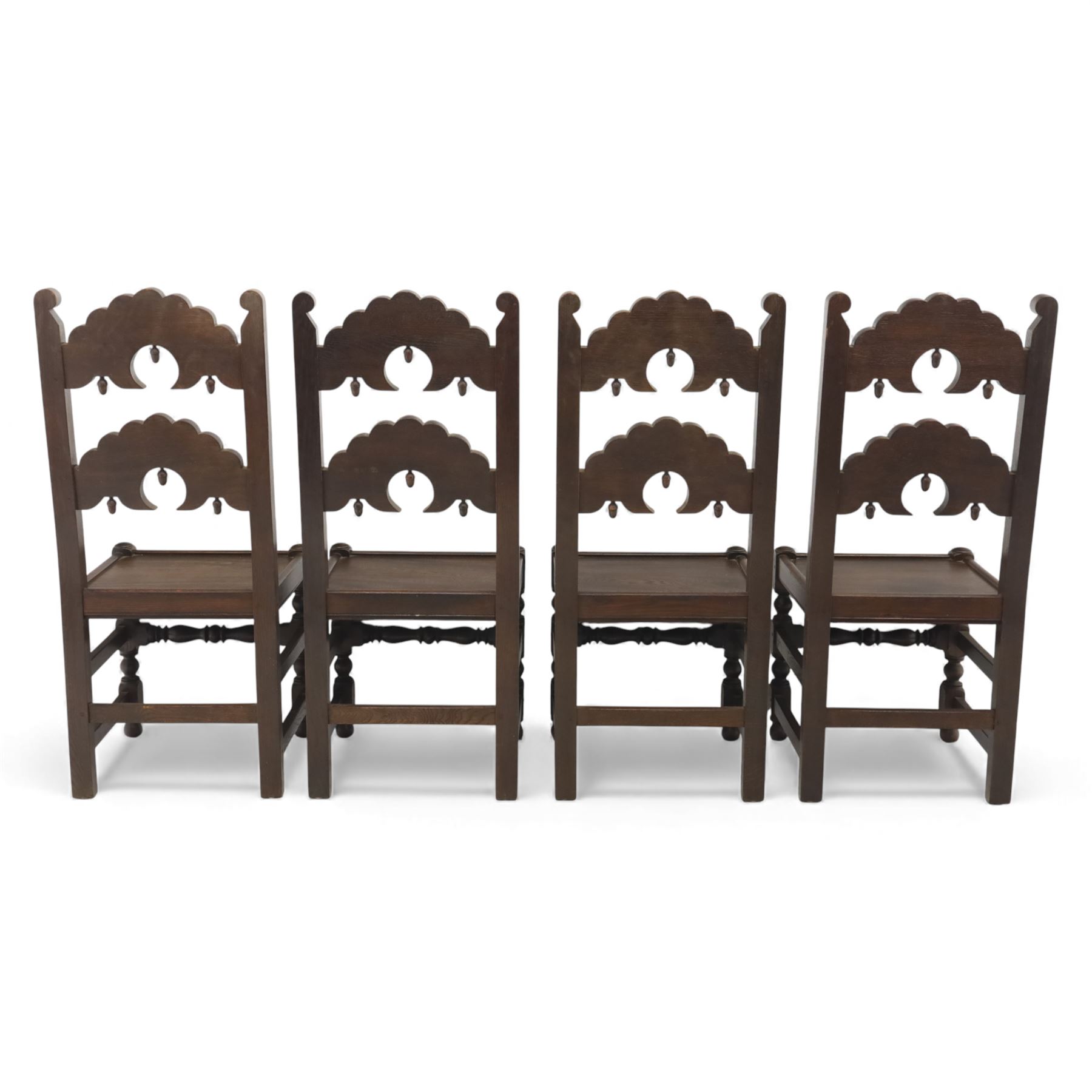 Early 20th century set of seven Jacobean Revival oak chairs, comprising pair of cavers and five chairs, each with carved mask and scroll decoration to the crest and and back rail, plain oak seat, upon turned front legs and block rear legs with conforming stretchers