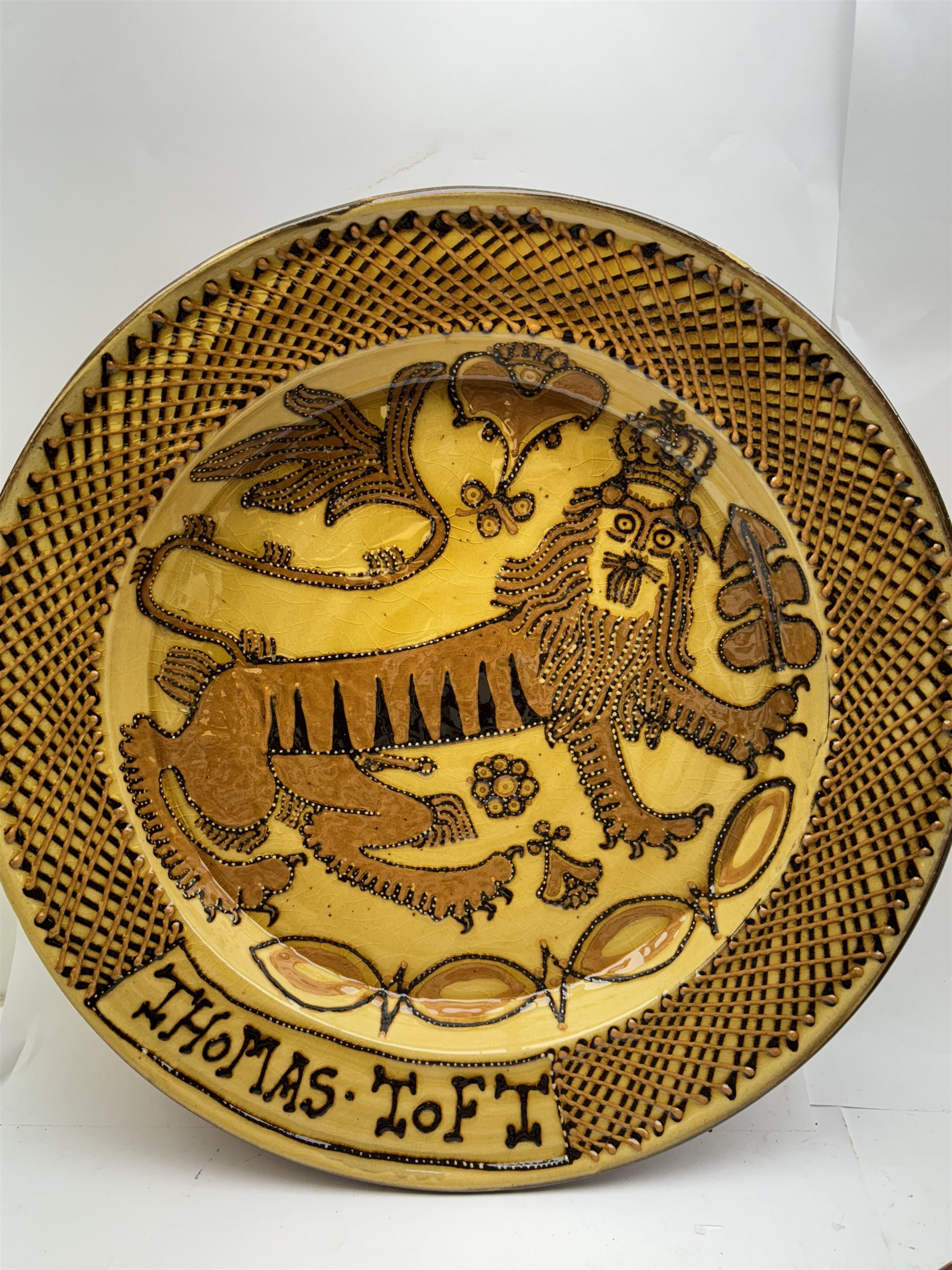 John Hudson: Large slipware charger in the style of Thomas Toft by John Hudson of Mirfield Pottery, decorated with the lion supporter taken by Toft from the Royal Arms, incised marks verso, D 44cm.
