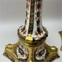 Pair of modern Royal Crown Derby Old Imari 1128 pattern candlesticks, each with shaped drip tray affixed to squat socket, upon spreading stem and canted square base with gilt dolphin edges, with printed marks beneath including Roman numeral year cypher for 2003, H26.5cm, with original boxes