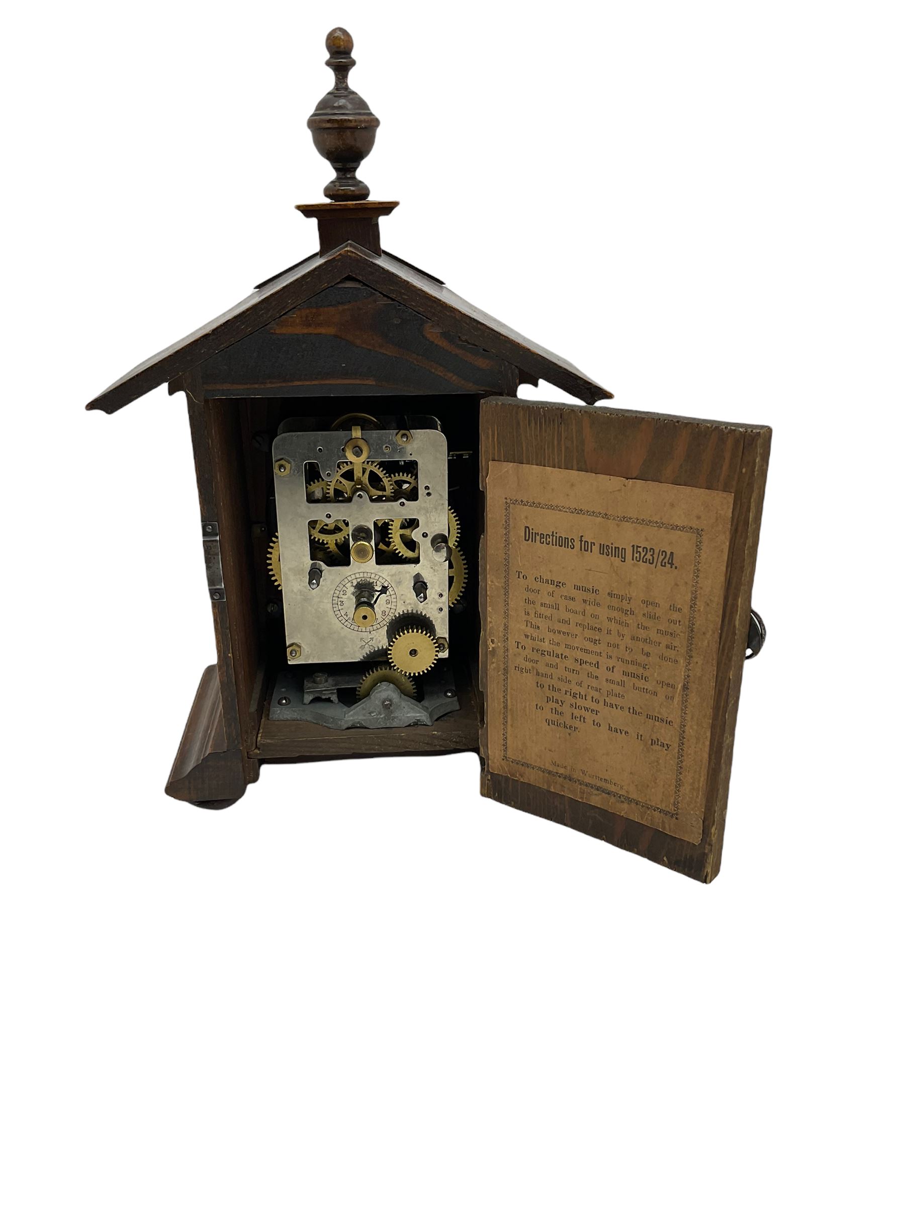 A German musical alarm clock (model 1523/24) made by the Hamburg Amerikanische Uhrenfabrik c1880, in an oak case with an architectural top and finial, two-part dial with a gilt centre, ivorine chapter and steel spade hands, with roman numerals and minute track, case raised on four bun feet, with a thirty-hour balance wheel pin pallet spring driven movement sounding the alarm on a musical movement, key wound and set from the rear. Compete with three different and changeable musical movements in their original box. These clocks would have been sold as here with separate musical movements, it is rare to find them with the original clock.
H30 W17 D11 

	



