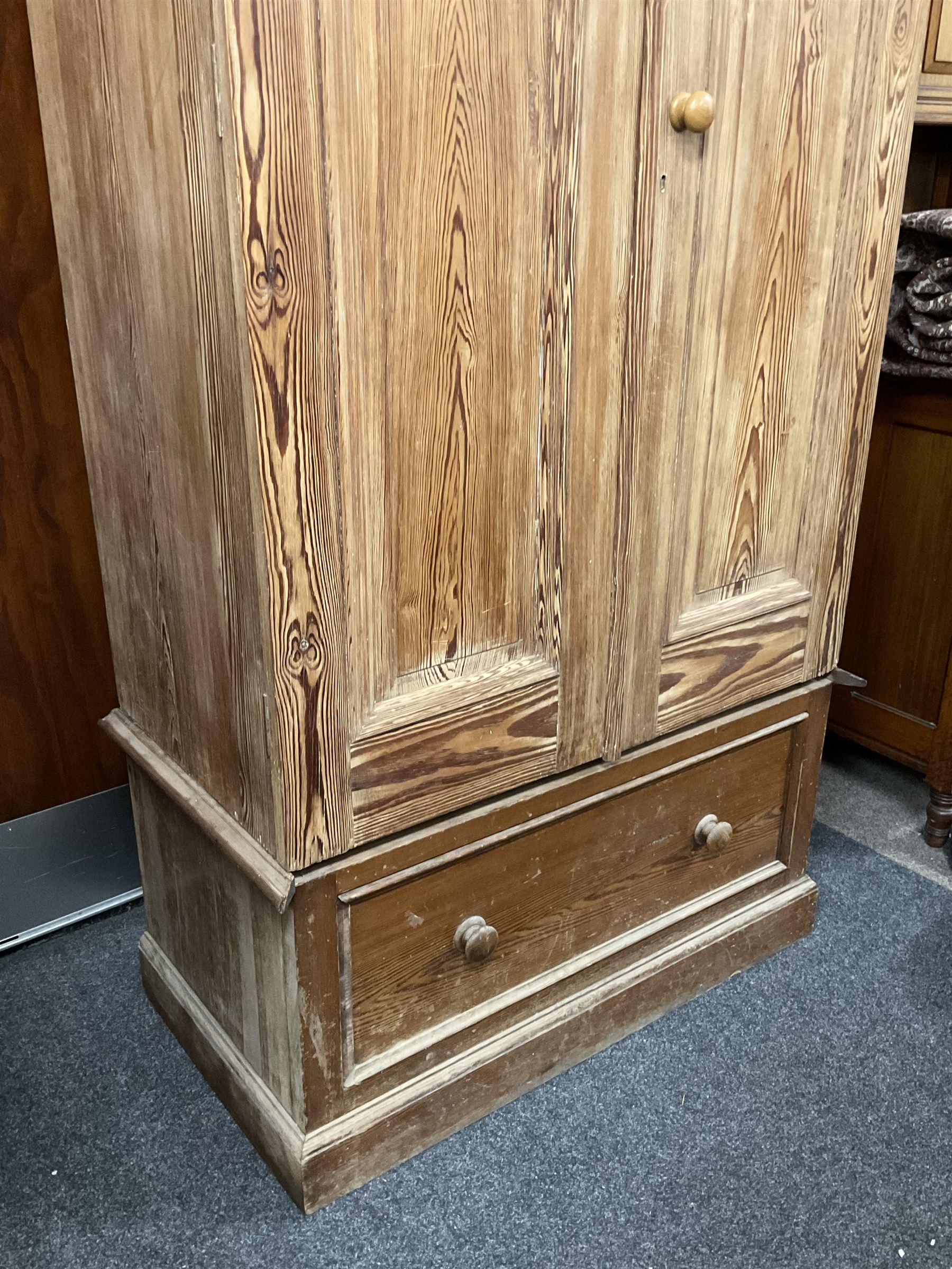 Victorian pitch pine double wardrobe, projecting moulded cornice over two panelled doors, the interior fitted with hanging rail and hooks, single drawer to base