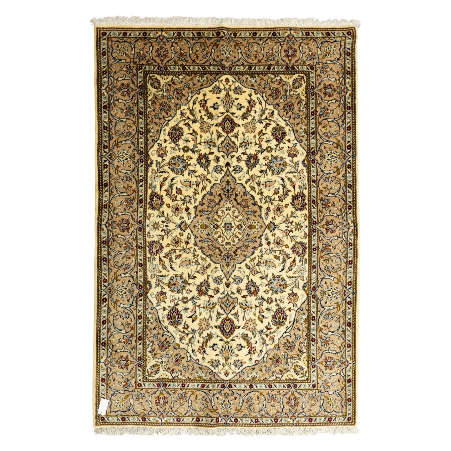 Central Persian Kashan hand-knotted rug, ivory ground, with a central shaped floral medallion with pendants, surrounded by scrolling foliate and floral motifs incorporating rosettes, palmettes and delicate vine work, enclosed by a beige border with repeating palmettes and meandering vines, flanked by narrow floral guard stripes, with cotton fringes