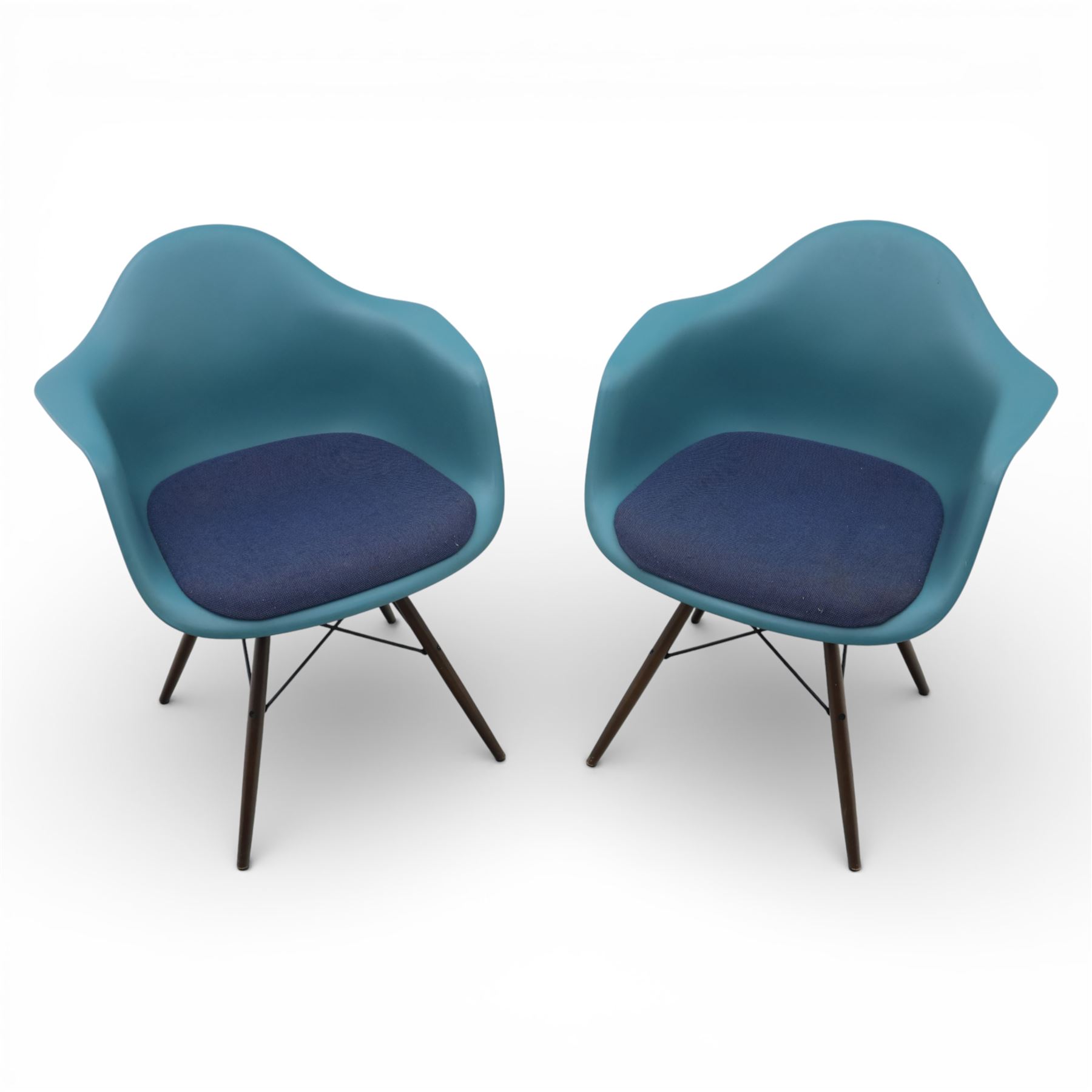 Vitra - Pair of Eames DAW armchairs, moulded plastic seats in teal with integrated armrests, blue upholstered seat cushions, supported on stained wooden dowel legs with black wire cross bracing