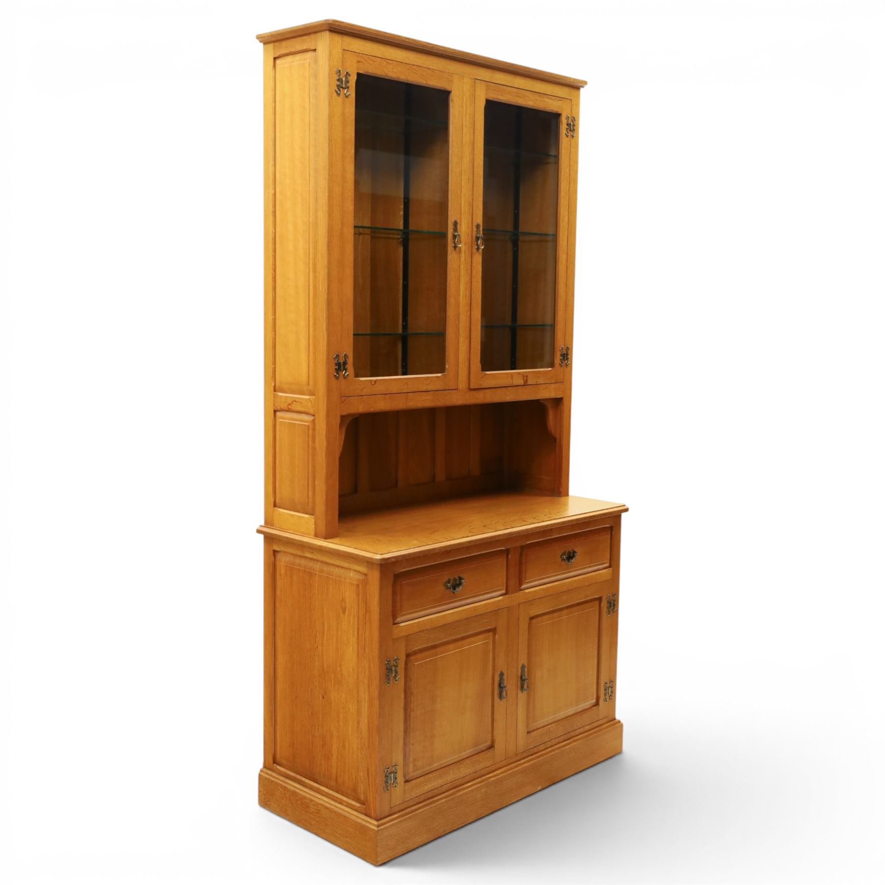 Knightman - oak dresser, the upper section fitted with twin glazed doors enclosing glass shelves, over open recess with panelled back, the base fitted with two drawers over twin panelled cupboards enclosing shelves, with recessed carved knight trademark, by Horace Knight of Old Mill Furniture, Balk near Thirsk