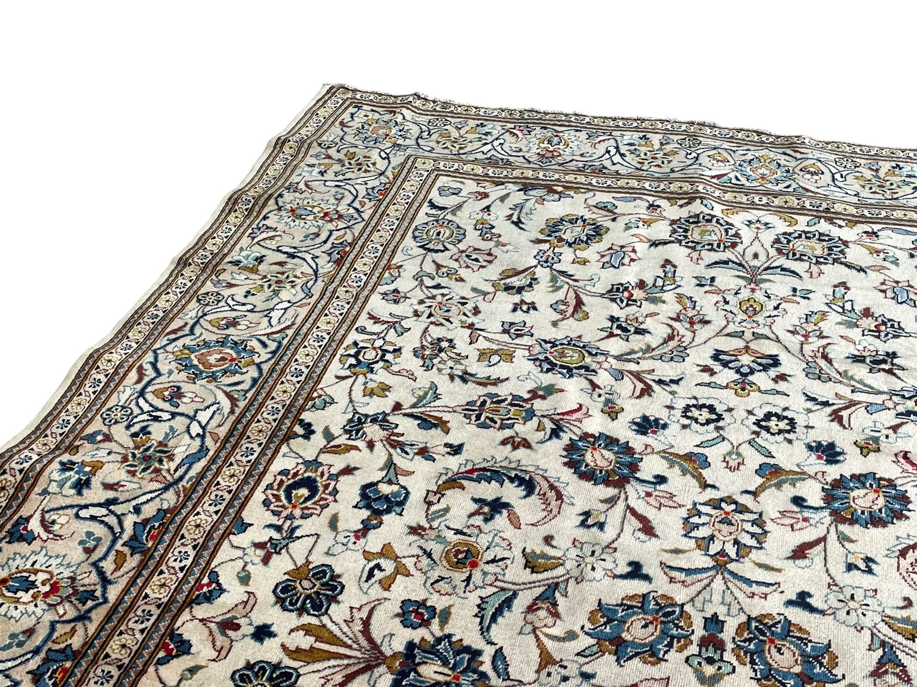 Persian Kashan ivory ground carpet, the field decorated with scrolling branches with foliate and palmette motifs, repeating border with stylised plant motifs, within floral and geometric pattern guard stripes 