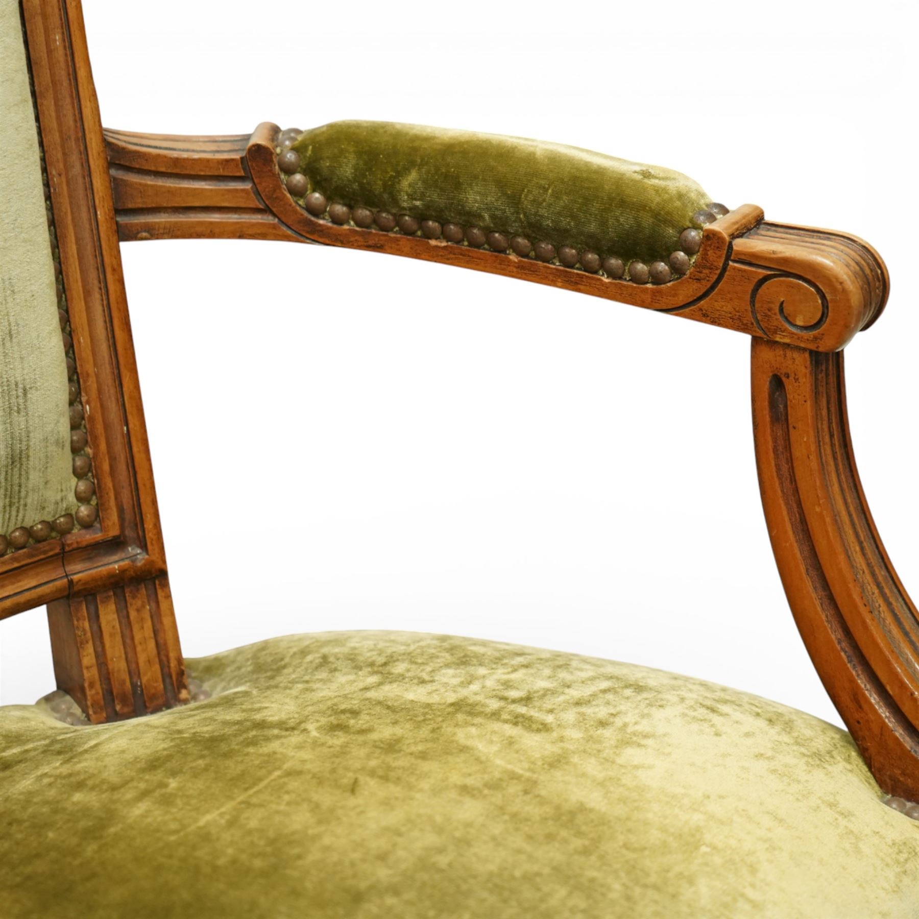 French Louis XVI style walnut armchairs, rectangular upholstered backs with nailhead trim, padded seats upholstered en suite, out-swept arms with upholstered pads, fluted supports with carved rosettes to the knees, on turned and fluted tapering legs