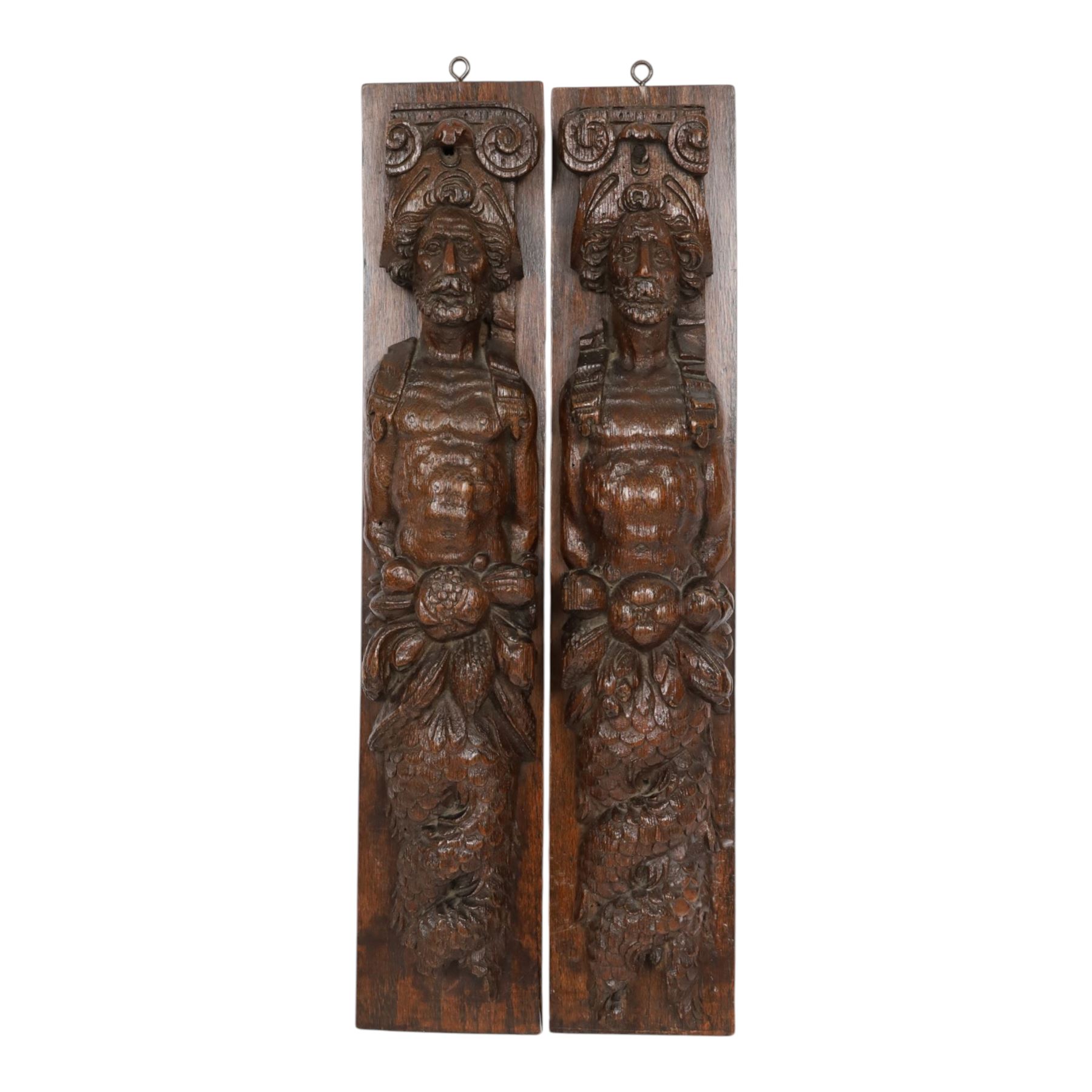Pair of 17th century carved oak terms, each depicting a male figure in headpiece, with fish tail beneath fruits, 51.5cm