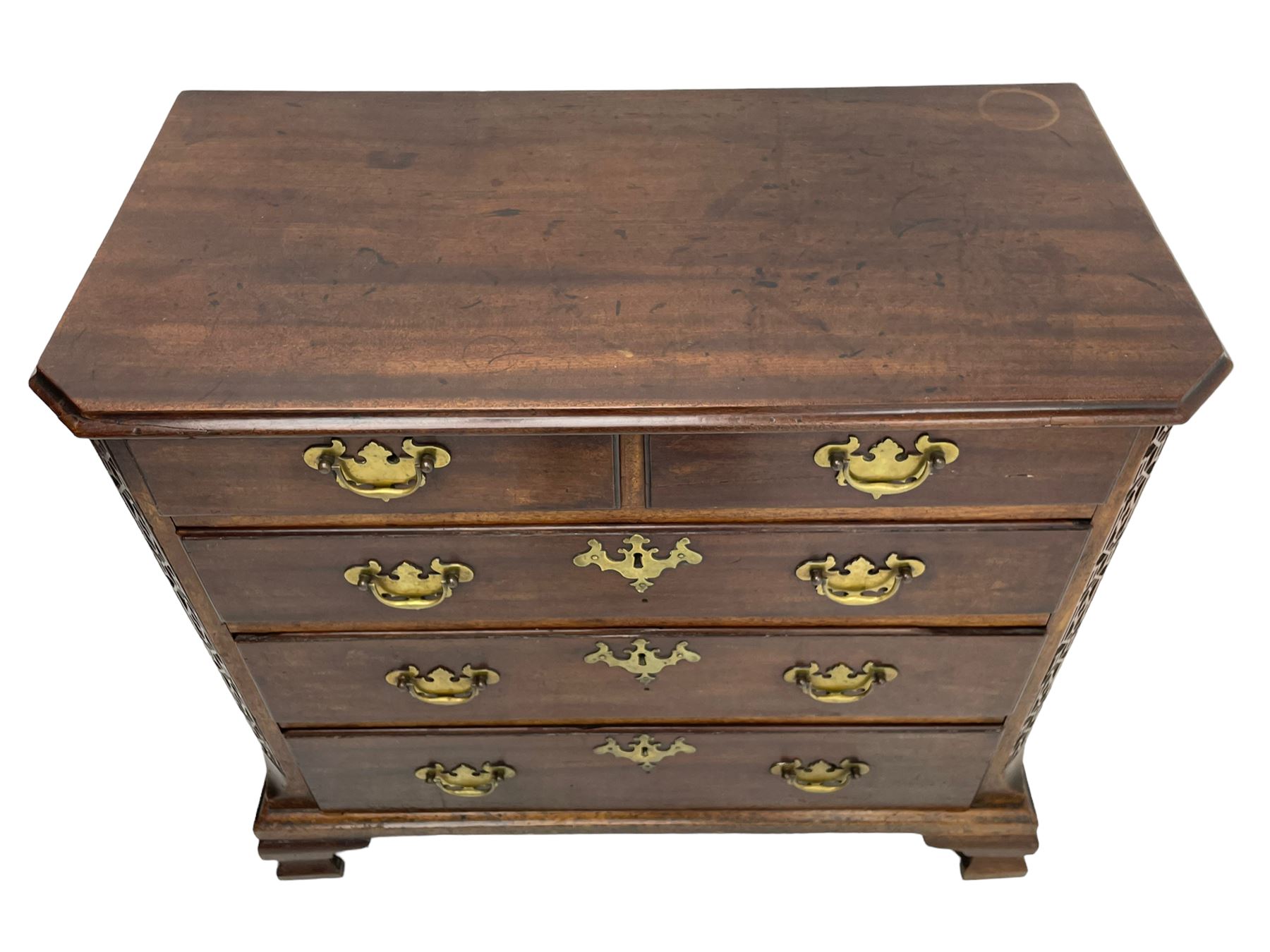 George III Chippendale design mahogany chest, moulded rectangular top with canted corners, wide canted uprights with blind fretwork decoration, two short and three long with moulded fronts, shaped brass handle plates, on ogee bracket feet 