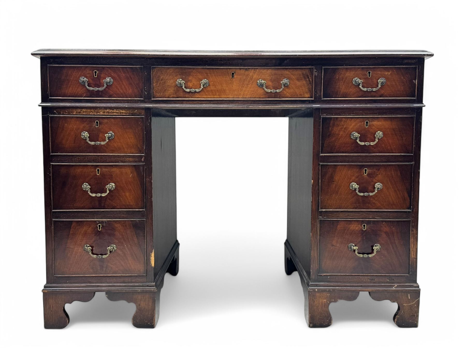 Georgian design mahogany kneehole desk, moulded rectangular top with red gilt-tooled leather writing surface, over an arrangement of nine cock-beaded drawers with brass swan neck handles, on bracket feet