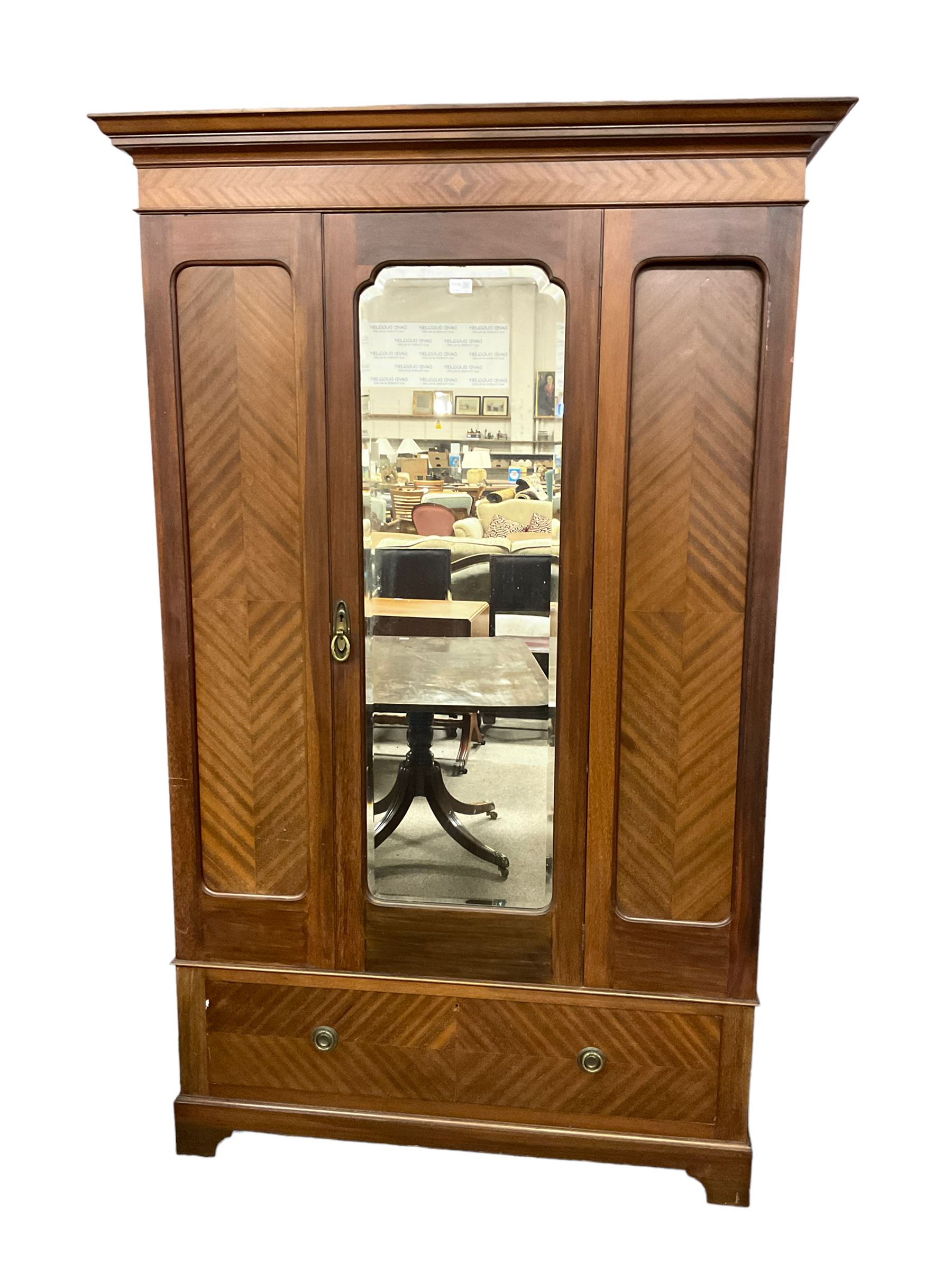 Edwardian mahogany single wardrobe, figured matched veneers to frieze, drawer front and panels, enclosed by bevelled mirror glazed door, base fitted with single drawer, on bracket feet