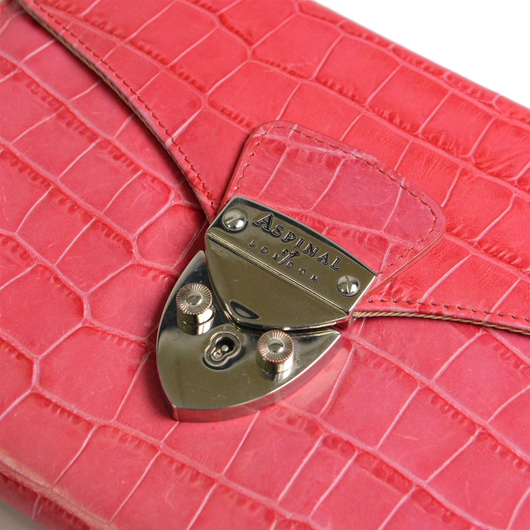 Aspinal of London fuchsia pink crocodile-embossed leather clutch bag with silver-tone shield-shaped clasp engraved Aspinal of London, the flap opening to a beige fabric-lined interior fitted with a zip pocket, slip pocket, integrated mirror and detachable chain shoulder strap, leather brand label stamped Aspinal of London England Fine Leather, accompanied by an Aspinal of London dust bag, W23cm H17cm