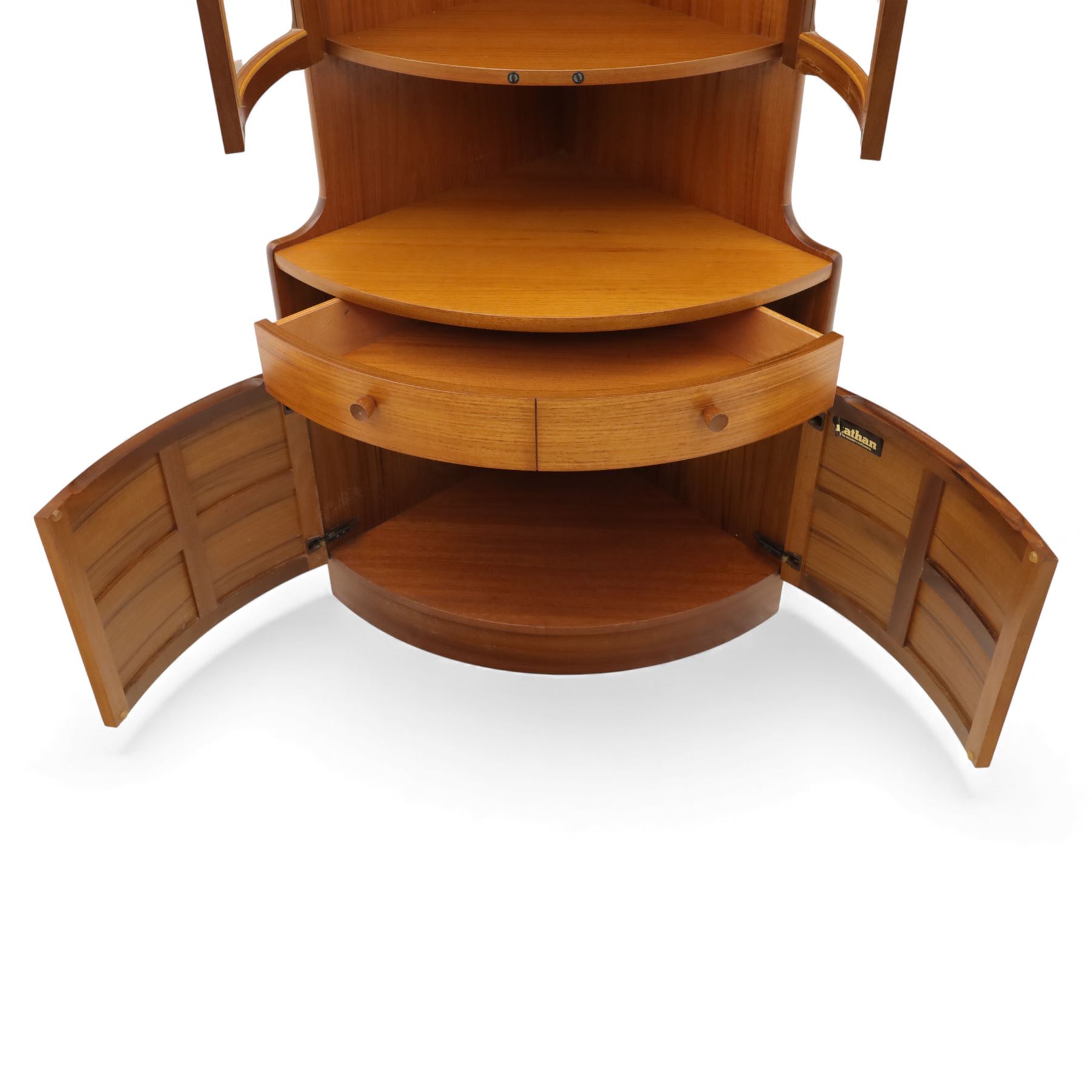 Nathan for Parker Knoll - corner cabinet, the upper section enclosed by two curved glazed doors with glass shelves, over a shaped base fitted with a single frieze drawer and panelled twin cupboard doors