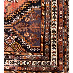 Southwestern Persian Qashqai hand-knotted carpet, the field with a lattice of hexagonal medallions in rust, indigo, and ochre, each containing stylised tree and floral motifs, flanked by lozenge panels with geometric designs, enclosed by multiple borders with rosettes and leaf motifs