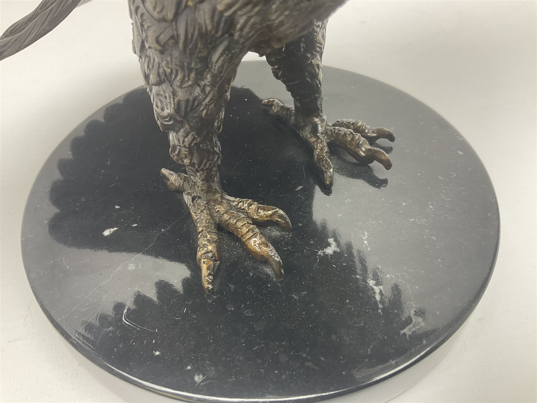 Bronze eagle, modelled in a standing position with wings spread, raised on a black veined marble circular plinth base, H29cm