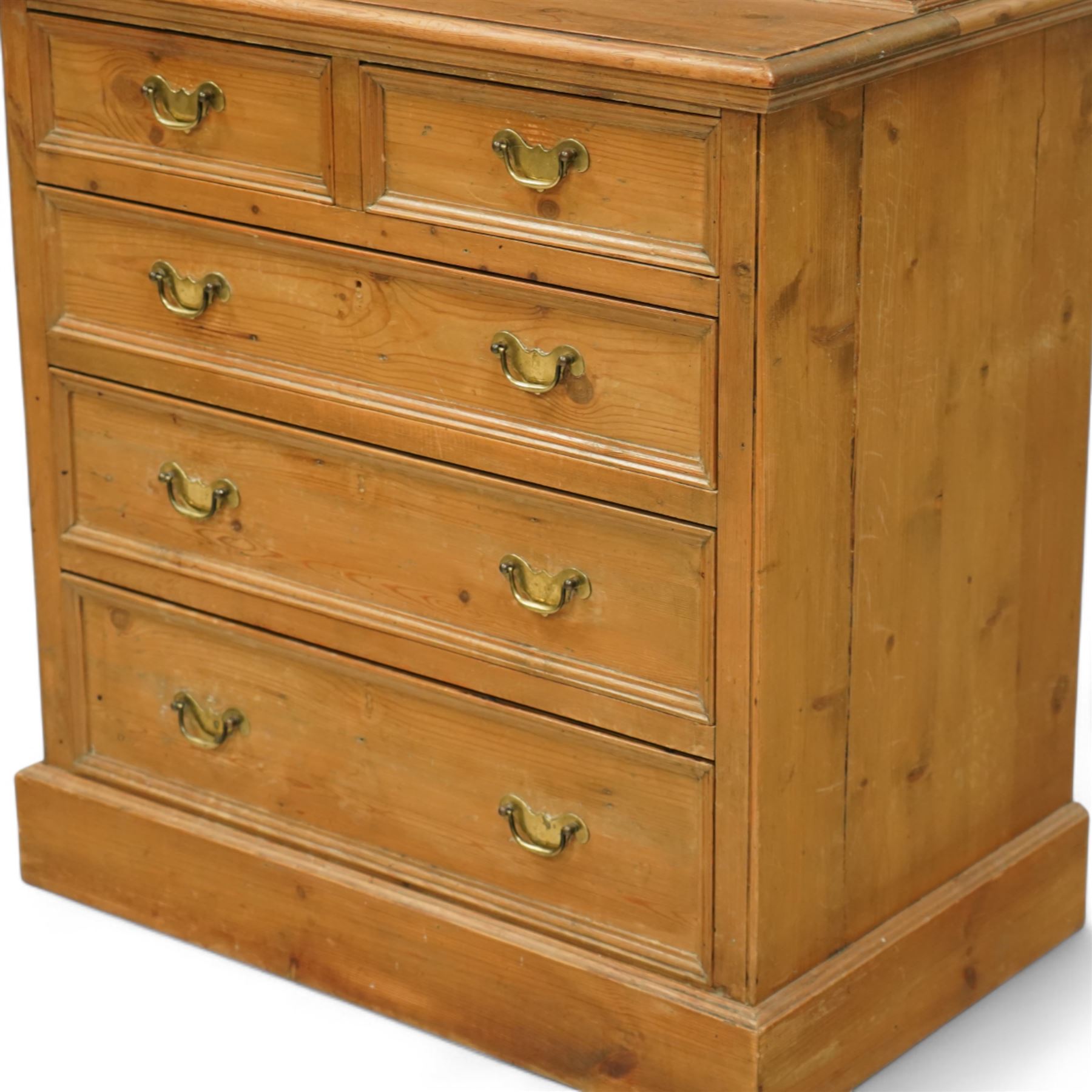 Early 20th-century pine gun cabinet with later fitted shelves, of two-part construction, upper cupboard moulded and dentil cornice above two panelled doors revealing three removable shelves and circular recesses for gun barrels at the top, lower section with two short and three long graduated drawers with brass swan neck handles on plinth base 