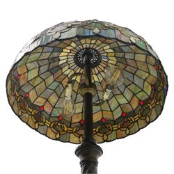 Late 20th century Tiffany style standard lamp, the leaded glass domed shade composed of geometric panels in mottled pastel tones, bordered by stylised foliate motifs and coloured cabochons, raised on a spiral twist metal column and circular moulded base