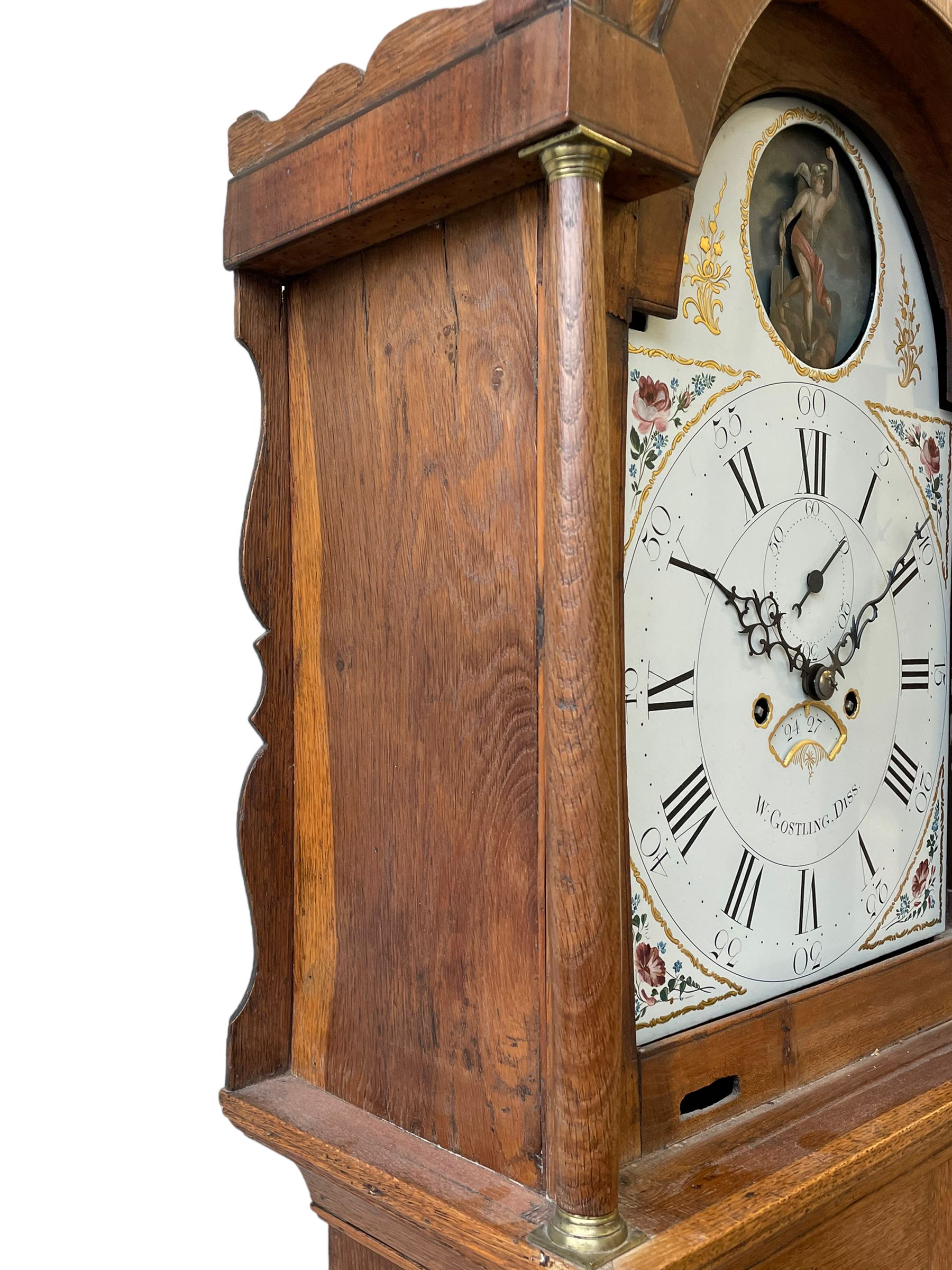 William Gostling of Diss  (Norfolk)-  Late 18th century 8-day oak longcase clock c1780-90, break arch top with scalloped cresting and three brass finials, glazed break arch hood door flanked by turned pilasters with brass capitals, trunk with a long trunk door and rounded top on a square plinth with an applied and shaped skirting, early painted Wilson of Birmingham dial with Roman numerals and five minute Arabic's, matching steel hands and second pointer, arched square ended calendar aperture with date disc behind, floral spandrels within gesso borders and a painted rocking automaton representing Mercury to the break arch, dial pinned via a false plate to a weight driven rack striking movement with a recoil anchor escapement, striking the hours on a cast bell. With pendulum weights and key. 
William Gostling (II) is recorded as working in Diss from 1774 to 1797, succeeded by widow Anne and son George . The dial of this clock is illustrated and discussed in detail in M.F. Tennants book 