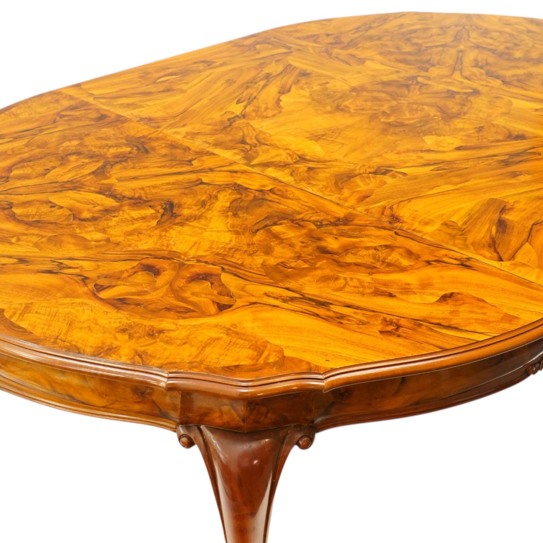 Dutch design figured walnut extending dining table, the shaped circular extending top with book-matched veneer and moulded edge, shaped banded frieze over scroll-moulded lower rail, raised on C-scroll carved cabriole supports with pad feet, with additional leaf