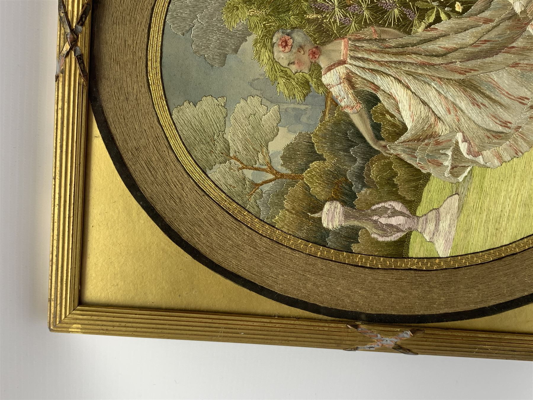 George III silkwork picture, of oval form depicting a female figure in garden setting, within a silkwork border detailed with verse from Robert Burns Bonnie Peg, 'Her air sae sweet, and shape complete, The Queen of Love did never move, Wi' Motion mair enchanting!', and monograms 'FV' and 'SM', in reeded gilt frame and gilt mount, indistinctly inscribed in pencil verso, overall H36cm L30.5cm
