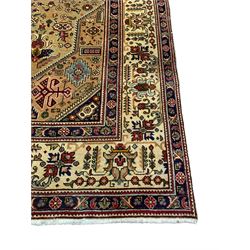 Persian Azarbaijan golden ground carpet, the shaped crimson ground medallion decorated with geometric motifs, the field profusely decorated with stylised plant and flower head motifs, repeating border with guard bands 