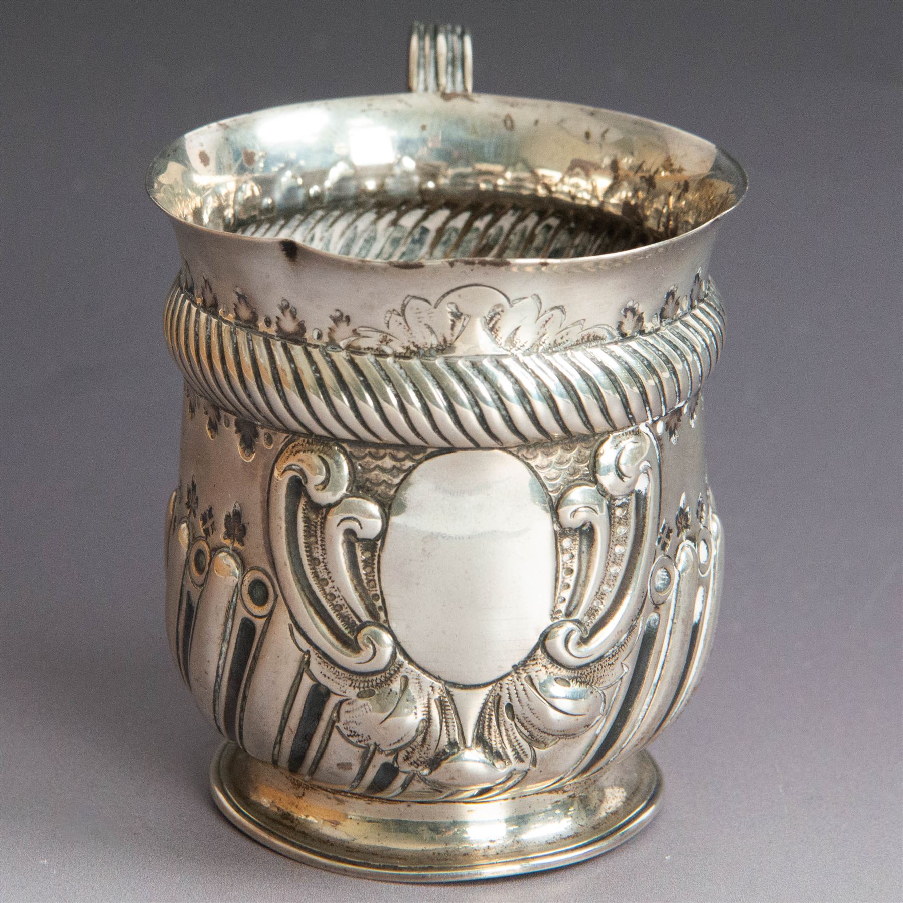 Victorian silver christening mug, of circular form with C scroll handle, embossed with scrolls and foliate decoration, with vacant oval cartouche to body, hallmarked John Aldwinckle & Thomas Slater, London 1890, contained within a tooled leather fitted case, mug H8cm