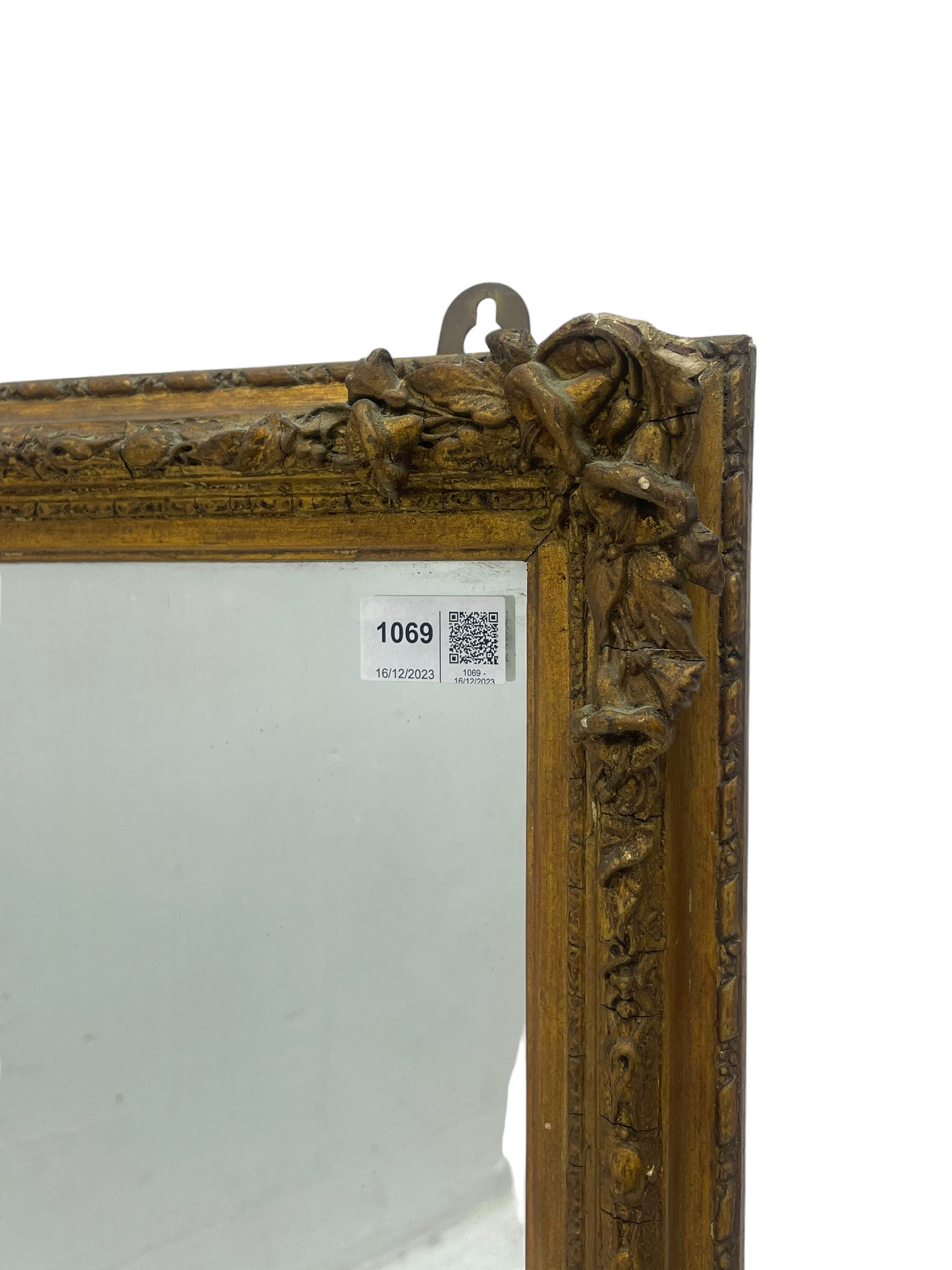 19th century gilt framed wall mirror, the corners decorated with flower heads with extending foliage, plain mirror plate