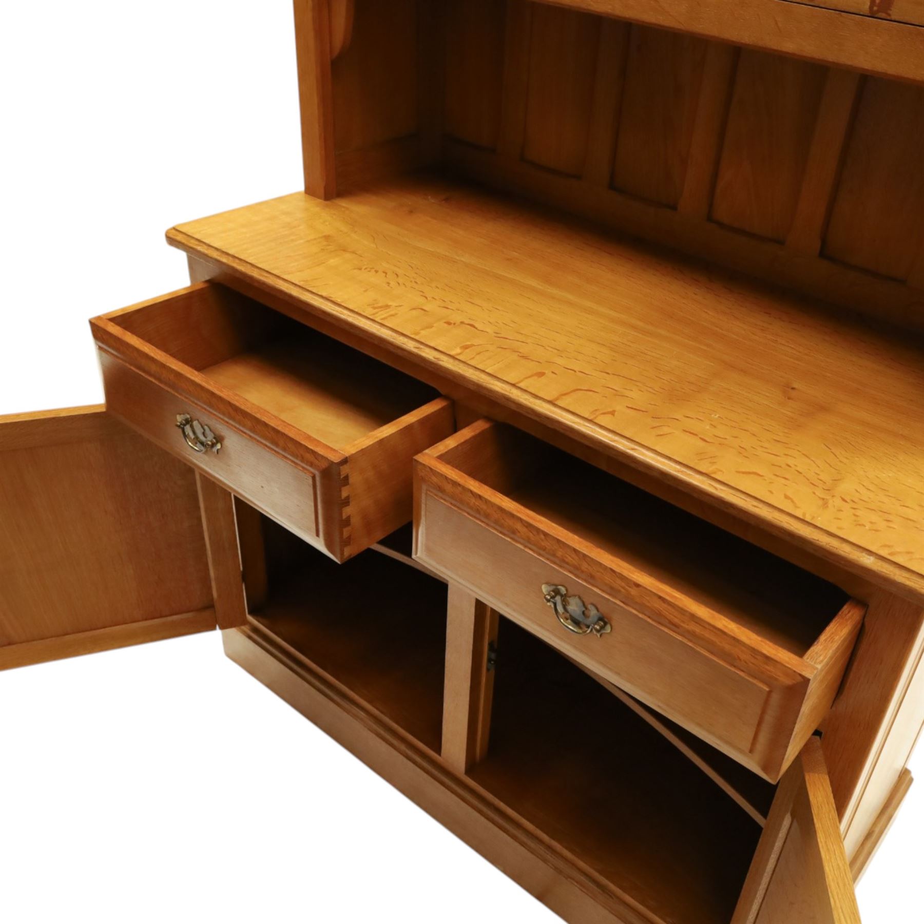 Knightman - oak dresser, the upper section fitted with twin glazed doors enclosing glass shelves, over open recess with panelled back, the base fitted with two drawers over twin panelled cupboards enclosing shelves, with recessed carved knight trademark, by Horace Knight of Old Mill Furniture, Balk near Thirsk
