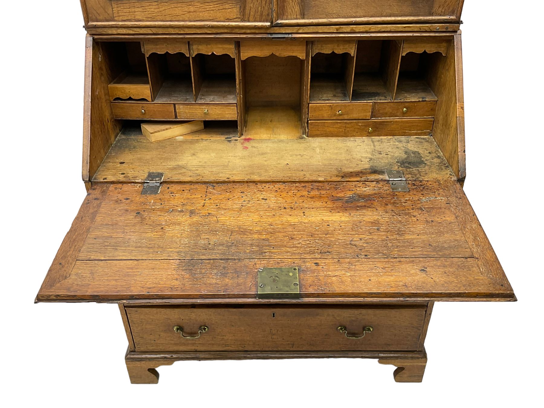 George III oak bookcase on bureau, the double arched top enclosed by two shaped glazed doors, fall-front concealing fitted interior, over four graduating cock-beaded drawers, on bracket feet