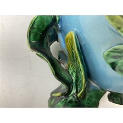 George Jones style majolica jardiniere of globular form, supported on four feet formed from modelled lily leaves growing up the side of the pot, with swallows flying amongst the white lily flowers, all set against a blue ground, with a pink interior, H27cm