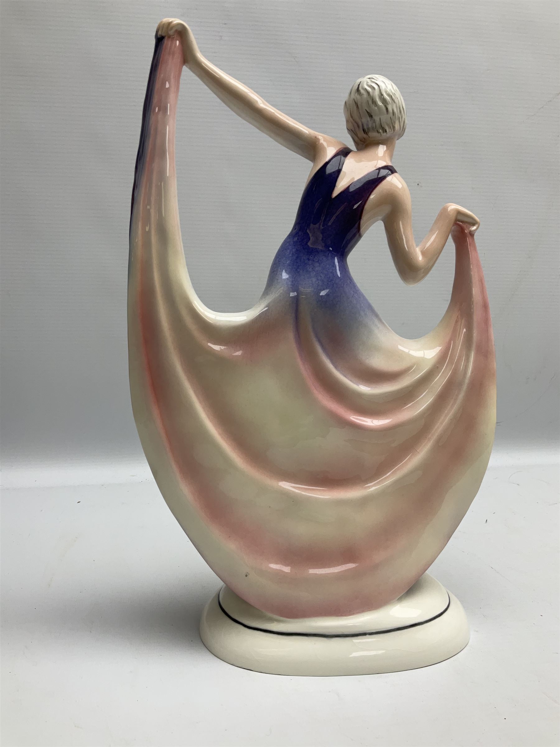 Early 20th century Hertwig Katzhütte figure of an Art Deco lady dancing, wearing a pink and purple dress, stood upon on a domed plinth, with green cat H house printed mark beneath, H32cm