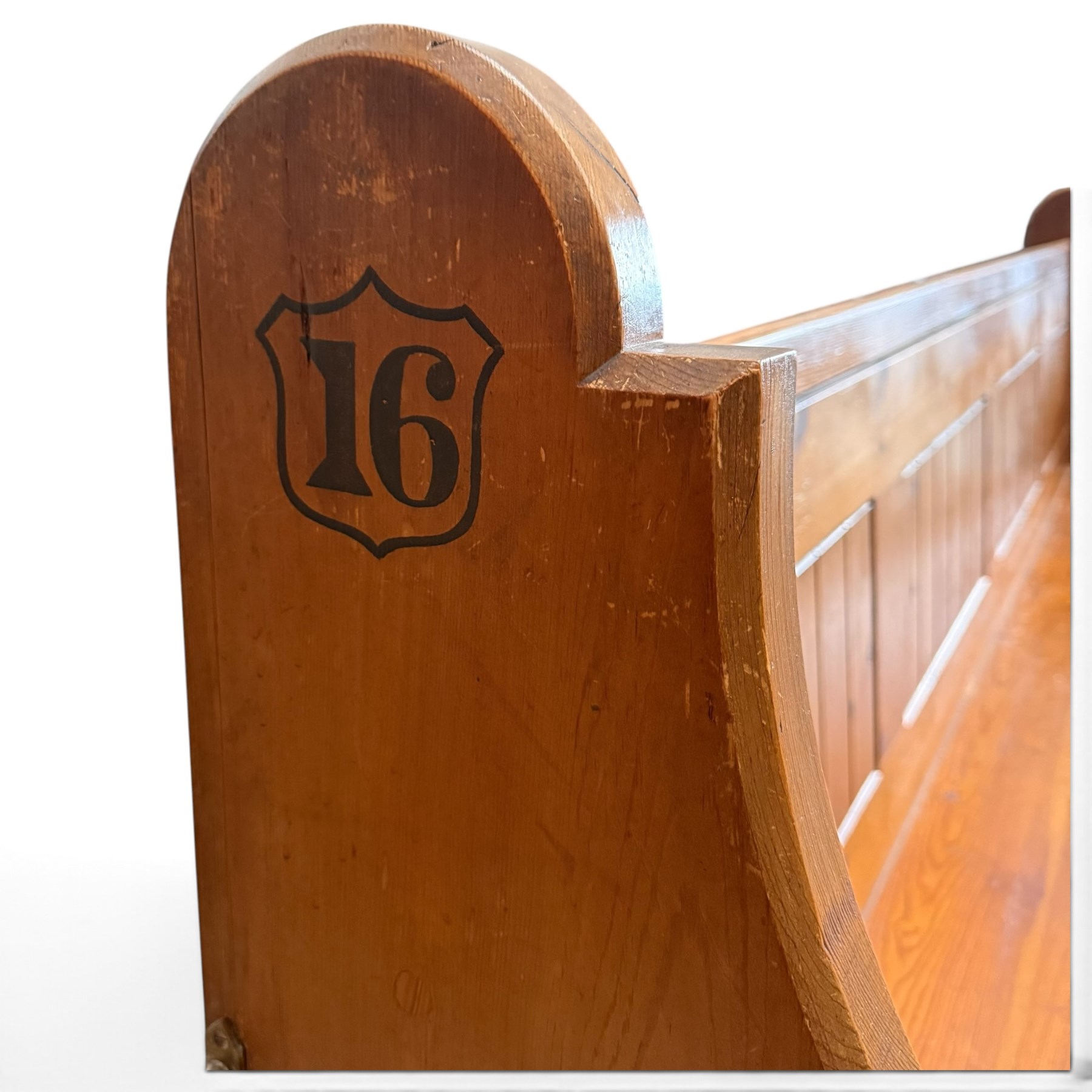Early 20th century stained pine ecclesiastical church pew, the shaped end supports flanking slatted and panelled back, with black stencilled number '16' to the side