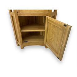 Contemporary light oak corner display cabinet, projecting cornice over single glazed door enclosing three glass shelves, the base fitted with panelled cupboard enclosing single oak shelf, on stile supports