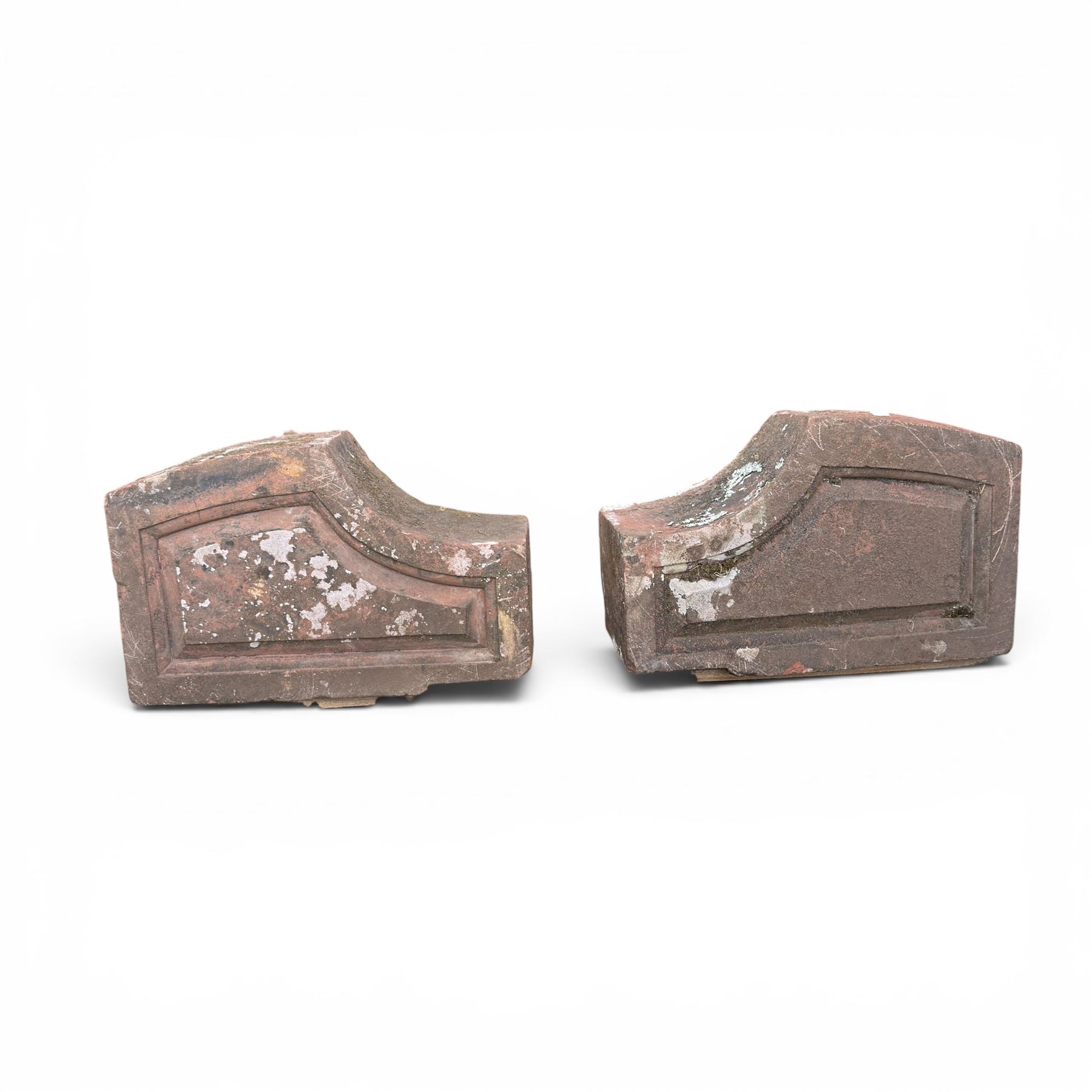 Pair of 19th century hewn and carved stone wall ends, the facias carved as shaped faux fielded panels