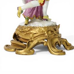 Mid 18th century Meissen figure group, The Tyrolean Dancers, circa 1740, modelled as two swirling figures with their arms linked, he in yellow hat with red rosette, blue jacket, red breeches with red rosette, and yellow shoes with green rosette, she in white blouse with red ribbons, yellow and red bodice, white apron over puce skirt and yellow shoes with green rosettes, her hair fashioned into two plaits secured by red ribbon, upon a shaped mound base, within a scrolling gilt metal mount, with blue crossed swords mark to base, overall H19cm
